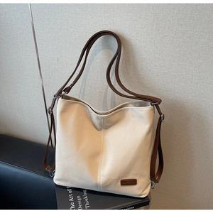 Detailed side view of off-white canvas tote bag with brown leather straps in a lifestyle setting