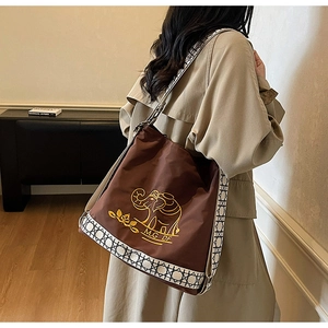 Detail of dark brown embroidered tote bag showing large capacity and shoulder strap texture