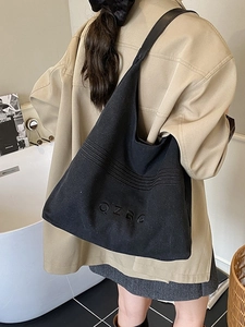 Minimalist black canvas tote bag with QZBG embroidery shown on shoulder for casual styling