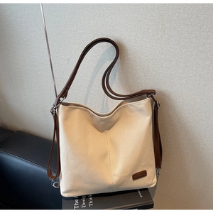 Close-up of minimalist canvas tote bag with brown leather straps and branded patch