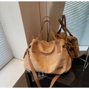Detail view of khaki canvas tote with adjustable strap and leather patch accents