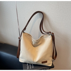 Close-up of beige canvas hobo bag featuring brown leather straps and metal buckle details