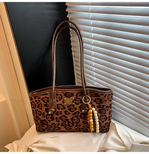 Close-up of leopard print tote bag with gold metal plate and wooden beaded tassel charm