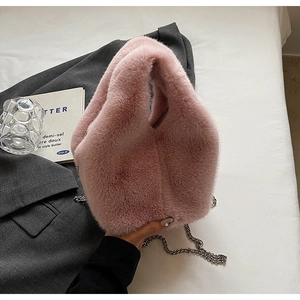Close-up of pink fluffy plush bucket bag with silver metal chain on grey blazer