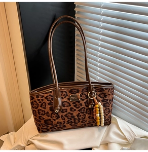 Detail of leopard print tote bag with brown leather strap and colorful beaded charm accessory