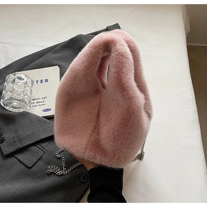 Detailed view of pink faux fur bucket bag with metal chain on a stylish backdrop