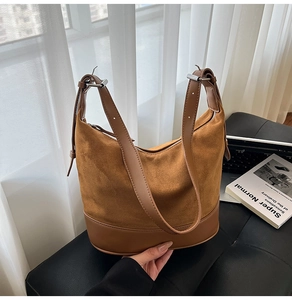 Dettaglio di borsa hobo in pelle e camoscio marrone con tracolla regolabile su divano