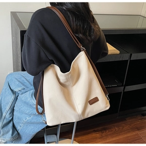 Detailed shot of a large beige canvas tote bag with slim brown leather shoulder straps