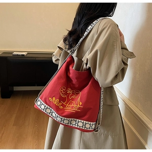 Detail of red canvas bucket bag with gold elephant embroidery and geometric strap