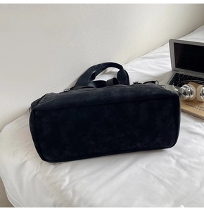 Macro shot of large black matte travel tote bag with silver hardware and fabric handles