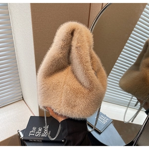 Detail view of plush faux fur bucket bag with silver chain strap on a vanity desk
