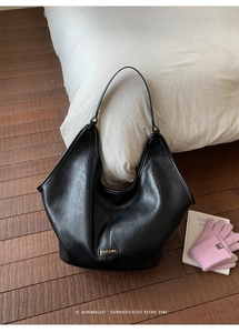 Detailed view of black retro Hobo bag with gold brand logo in a cozy home setting