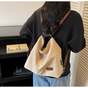 Detail of beige canvas tote bag with adjustable brown leather strap and brand logo