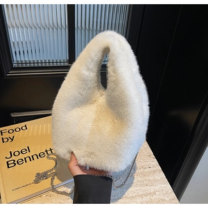 Detail of white plush bucket bag showing soft faux fur texture and silver metal chain strap