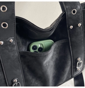 Detailed shot of black tote bag featuring silver rivets and phone pocket storage space