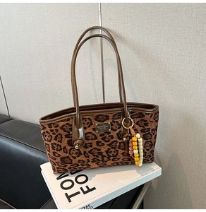 Close-up of leopard print tote bag with gold logo plate and beaded tassel detail