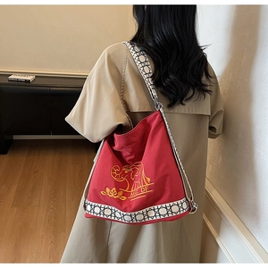 Detail of red canvas tote featuring elephant embroidery and woven geometric strap accents
