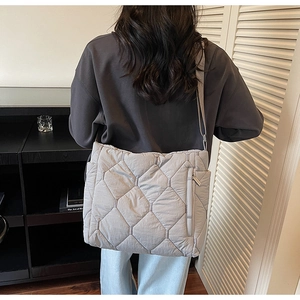 Detailed view of the diamond-quilted nylon puffer bag featuring a side zipper pocket