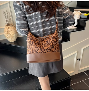 Dettaglio della borsa a secchiello leopardata con base in pelle marrone su modella