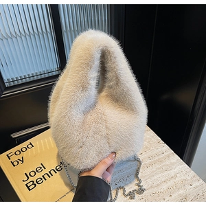 Close-up of soft faux fur bucket bag in cream white with a sleek silver chain strap
