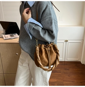 Détail du sac seau en daim marron avec poignée tressée torsadée et cordon de serrage