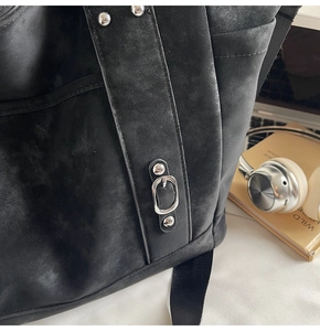 Close-up of vintage black matte tote bag featuring silver studs and buckle details