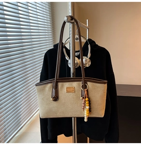 Detail of the suede tote bag with brown leather trim and bohemian beaded charm