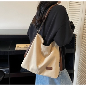Close-up of minimalist beige canvas tote bag with brown leather straps and brand logo