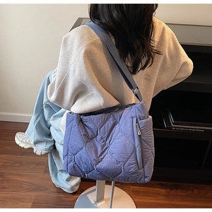 Quilted light blue puffer tote bag with side zippers and wide strap on model