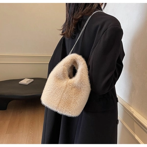Detail view of a fluffy beige faux fur bucket bag with a stylish silver chain strap