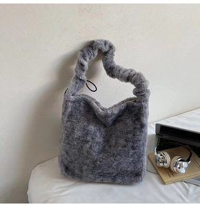 Grey plush tote bag with ruffled handle detail styled next to a laptop and books