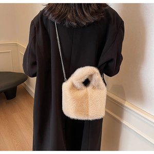 Close-up of fluffy faux fur bucket bag with a sleek metal chain strap on black coat