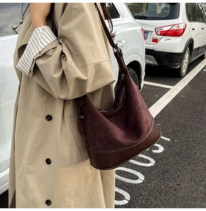 Dettaglio della borsa a secchiello in pelle e camoscio bordeaux su un trench beige