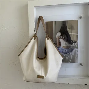 Detail of creamy white PU leather tote bag showing lychee texture and brown contrast trim