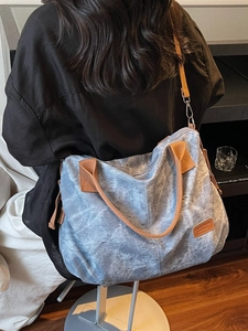 Large blue cloud-pattern canvas tote bag with brown straps worn over the shoulder