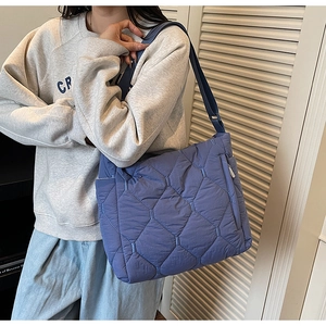Detail view of quilted blue tote bag showing soft puffer material and wide strap
