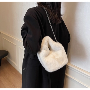 Close-up of white plush bucket bag with silver chain strap on a black winter coat