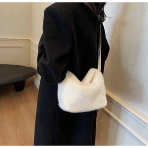 Dettaglio di una borsa a secchiello in finta pelliccia bianca con cappotto nero invernale