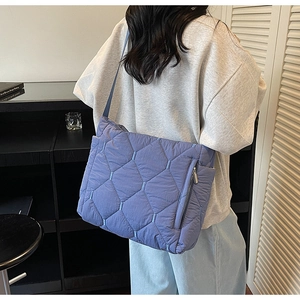 Detail shot of blue quilted puffer tote bag featuring side zipper pocket and nylon texture