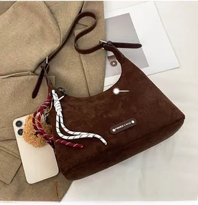 Détail d'un grand sac hobo en daim marron avec étiquette mode et charm d'ours peluche