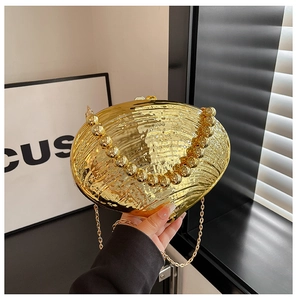 Detail of shell-shaped gold acrylic evening clutch with beaded handle and metal chain strap