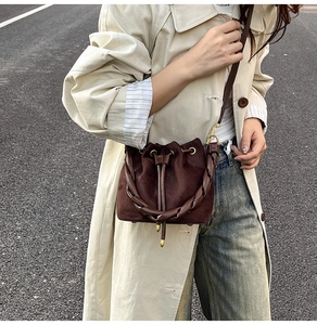 Détail d'un sac seau en daim marron foncé avec cordon décoratif et poignée tressée