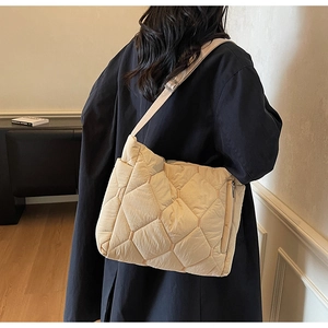 Detail of beige quilted cotton padded crossbody bag featuring elegant rhombus stitching texture