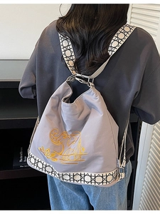 Gray canvas backpack with elephant embroidery and geometric strap shown on a model