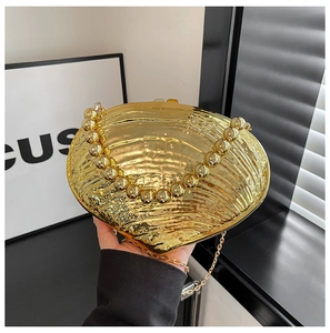 Close-up of golden shell evening bag with beaded handle and fine metal chain strap