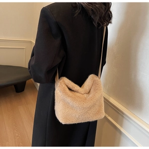 Dettaglio di una borsa a secchiello beige in finta pelliccia su un cappotto di lana