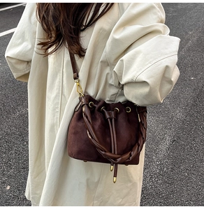 Détail du sac seau en daim marron foncé avec poignée tressée et fermeture à cordon