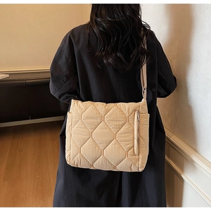 Close-up of beige quilted tote bag showing diamond stitch patterns and a zip pocket