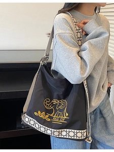 Black canvas bucket bag with gold elephant embroidery and patterned wide shoulder strap