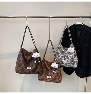 Detailed display of trendy paisley shoulder bags with plush cloud charms and branded tag